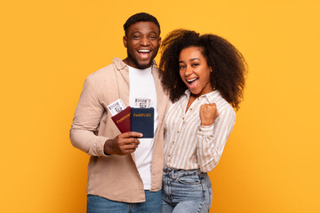 Joyful black couple with passports ready to travel - obrazy, fototapety, plakaty