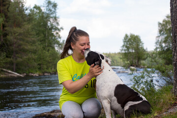 A woman on a walk with a dog against the background of a river threshold. Republic of Karelia wild...