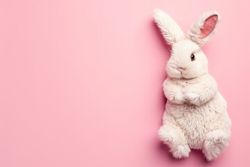 Top view of a white toy rabbit on a pink background with space for copy Easter theme - obrazy, fototapety, plakaty