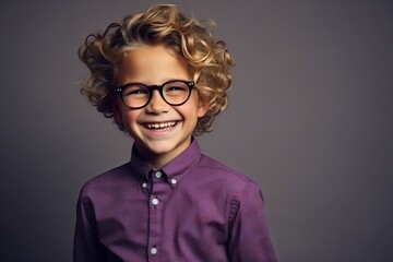 Portrait of a cute little boy with curly hair wearing glasses.