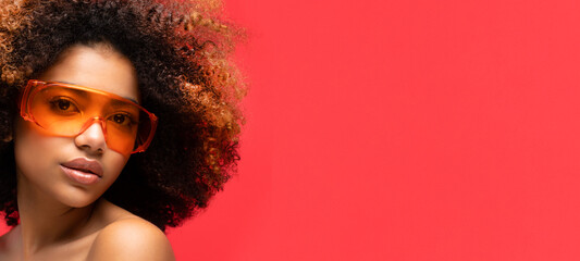 Happy Afro woman wearing eyeglasses smiling, isolated on studio red background.