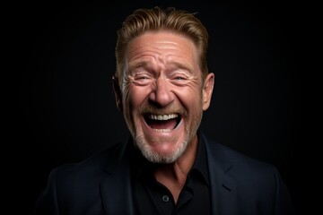 Portrait of a senior man laughing against a dark background. Studio shot.