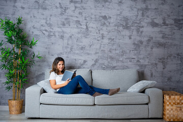 Peaceful and relaxed woman lying on the sofa reading a book