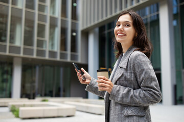 lady using her smartphone standing with her morning coffee outdoor