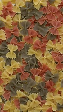 Italian tricolore farfalle pasta background. Table spin. Vertical video.