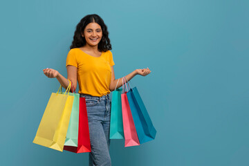 Excited young indian woman holding colorful shopping bags