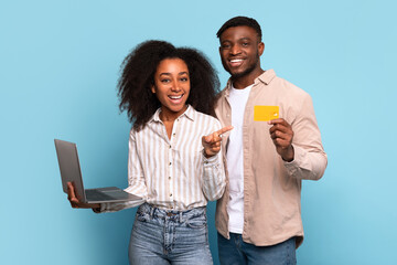 Cheerful african american couple with laptop and credit card - obrazy, fototapety, plakaty