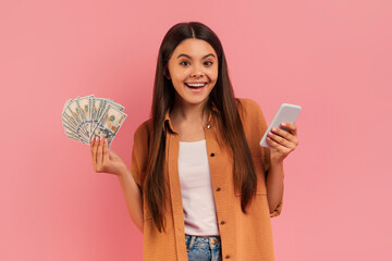 Cheerful teenage girl holding cash in one hand and smartphone in other