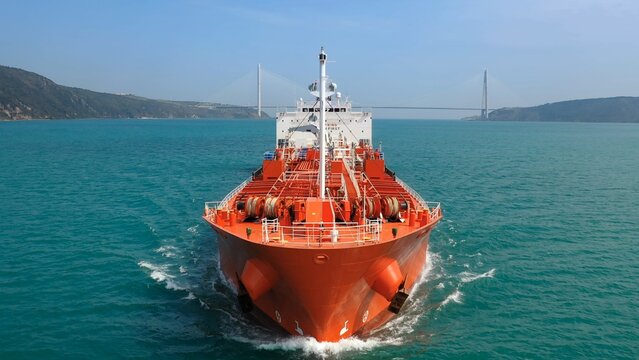 Supertanker loaded with crude oil sails towards the camera at full speed in the Bosphorus Sea. Red prow, bow, front deck, pipe lines and winches of oil products tanker underways ocean. Aerial Drone
