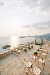 Rows of chairs stand in front of a round wedding arch on the observation deck above the island of Sveti Stefan. Montenegro