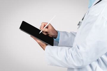 Man doctor using stylus on tablet for patient records