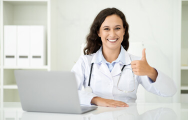 Positive european woman doctor working on laptop at clinic - obrazy, fototapety, plakaty