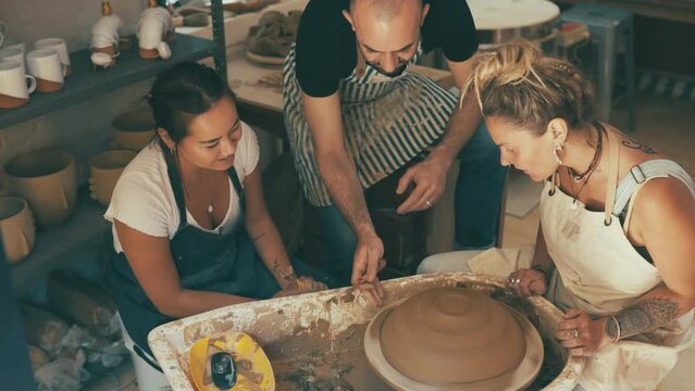 Pottery wheel, teacher and class of people learning workshop skill, sculpture design or craftsmanship. Ceramic studio, mentor and students teamwork on handmade product, creative project or mud art