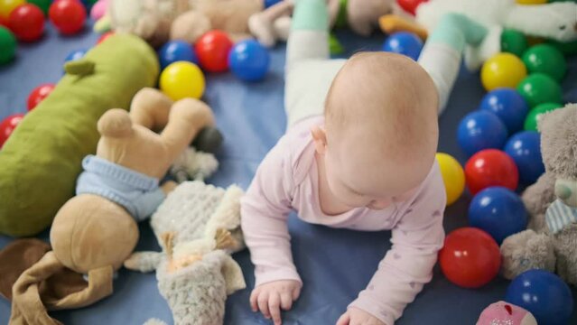 Cute baby girl playing with colorful toys in the nursery at home