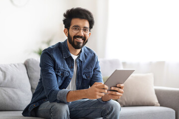 Millennial Eastern Man Spending Time With Digital Tablet At Home