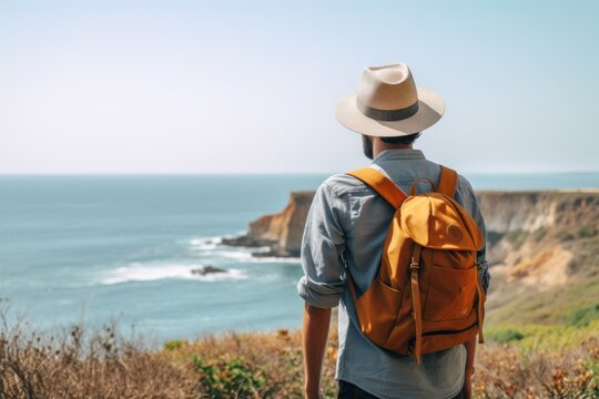 Man standing on a cliff and looking at the horizon with a backpack and a hat Ai Generative