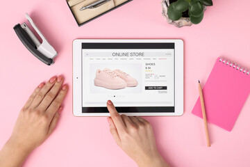 Woman with tablet shopping online on pink background, top view