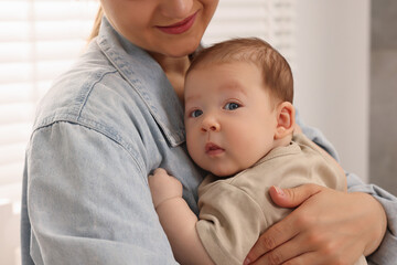 Mother holding her cute newborn baby indoors, closeup