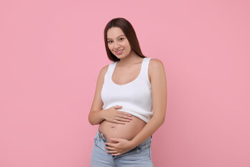 Beautiful pregnant woman with long hair on pink background
