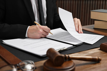 Lawyer working with documents at wooden table in office, closeup