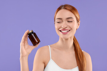 Happy young woman with bottle of pills on purple background. Weight loss