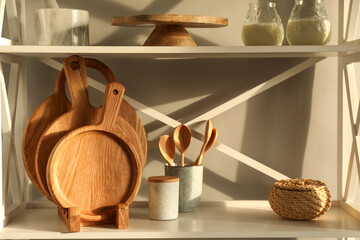 Wooden cutting boards, kitchen utensils and decor on shelving unit