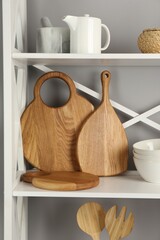 Wooden cutting boards and kitchen utensils on shelving unit