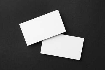 Blank business cards on black background, flat lay. Mockup for design