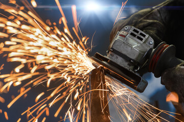 angle grinder, handyman worker using power tools grinding metal in a factory