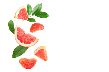 Fresh grapefruit pieces and green leaves falling on white background