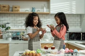 Two Asian adorable children sibling making a cake in kitchen at house.