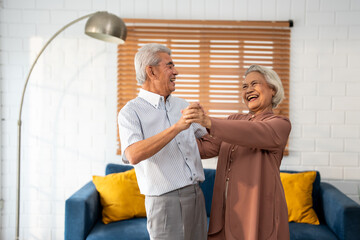 Asian active senior couple enjoy dance together in living room at home.