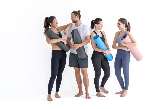 Group of happy sporty girls and guy wearing body stylish sportswear holding personal carpets leaned on a white background. waiting for yoga class or body weight class. healthy lifestyle and wellness