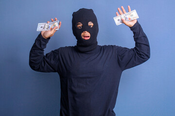 Male thief wearing black balaclava get caught red handed with hands full of money 