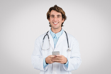 Fototapeta premium Smiling doctor using smartphone for healthcare apps