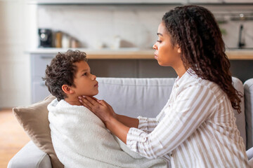 Black mom taking care of her sick son suffering from sore throat,