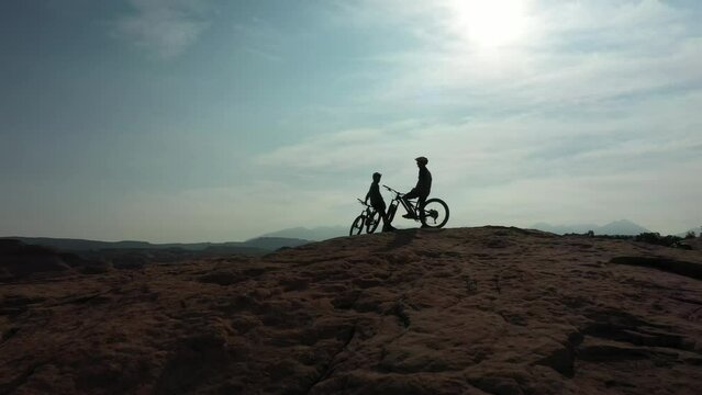 Mountain bike, extreme sports and silhouette or people relax during outdoor ride, desert journey or off road cycling. Sky, team conversation and dark shadow of cyclist on break after bicycle practice
