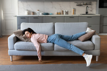 Tired woman resting on sofa after housework