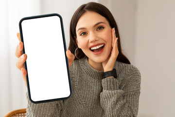 Excited young lady showing smartphone with white screen