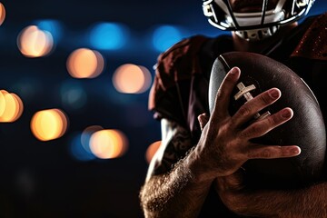 Close-up of an American football sportsman's hands gripping the ball, the stadium's lights creating a focused scene, with copy space for the narrative of skill, practice, and precision.