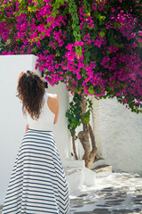Female tourist white dress exploring streets of Mykonos, Greece