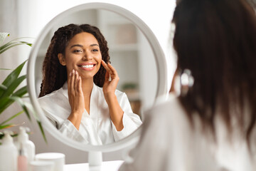 Beautiful black woman at home admiring her reflection in the mirror