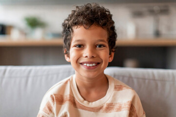 Cheerful black boy with curly hair and bright smile looking at camera - obrazy, fototapety, plakaty