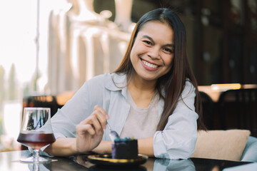Young woman is happy and enjoys eating sweets and coffee at a cafe.