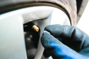 Car mechanic hand remove or close a tire valve cap of car wheel , Car maintenance service concept