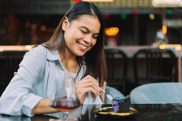 Young woman is happy and enjoys eating sweets and coffee at a cafe.