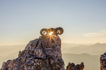 binoculars on top of rock mountain at beautiful sunset background.