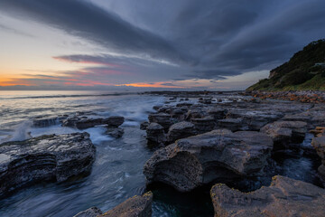 Rocky beach shore with cloudy sky in the morning.