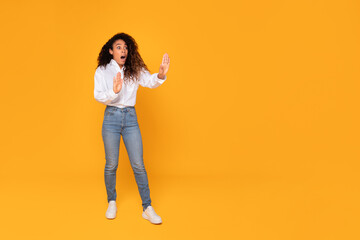shocked black woman standing showing stop gesture over yellow background