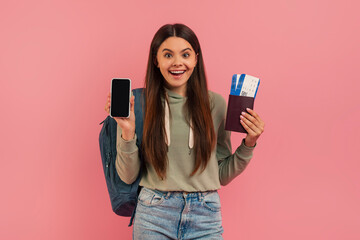Joyful teenage girl showing blank smartphone and holding passport with boarding passes - obrazy, fototapety, plakaty